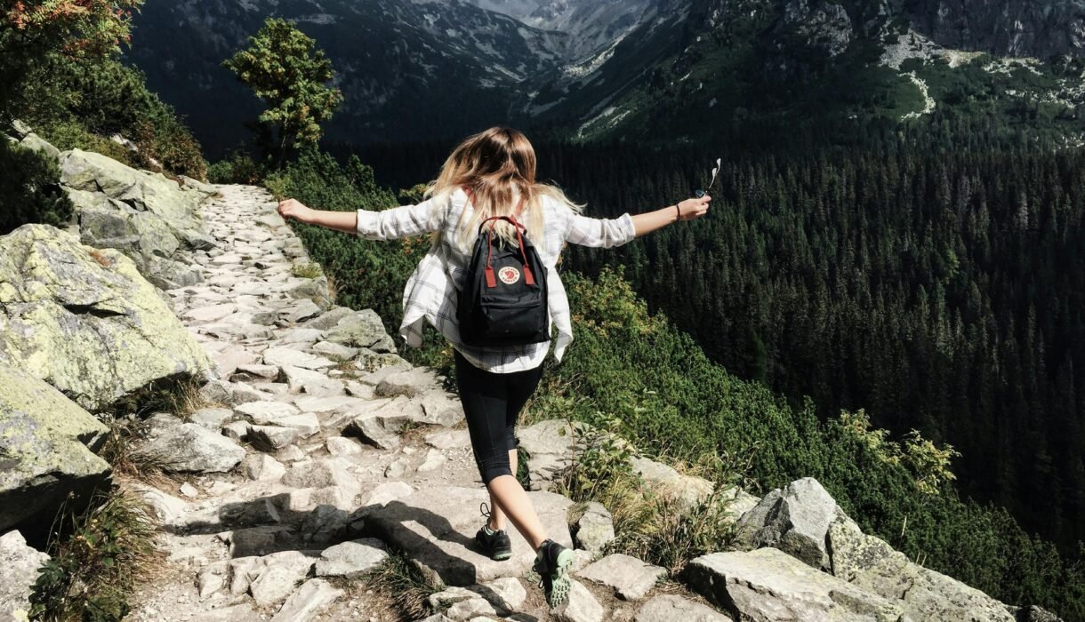 Woman hikes along rocky path in Vysoké Tatry, Slovakia. Embracing nature and freedom.