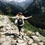 Woman hikes along rocky path in Vysoké Tatry, Slovakia. Embracing nature and freedom.