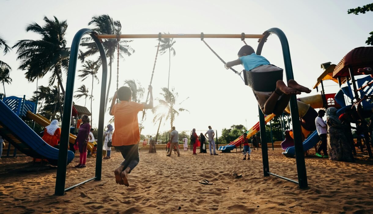Kids swinging and enjoying a fun day at a tropical playground.