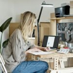 A young woman managing her online store startup, working diligently from her home office in Portugal.